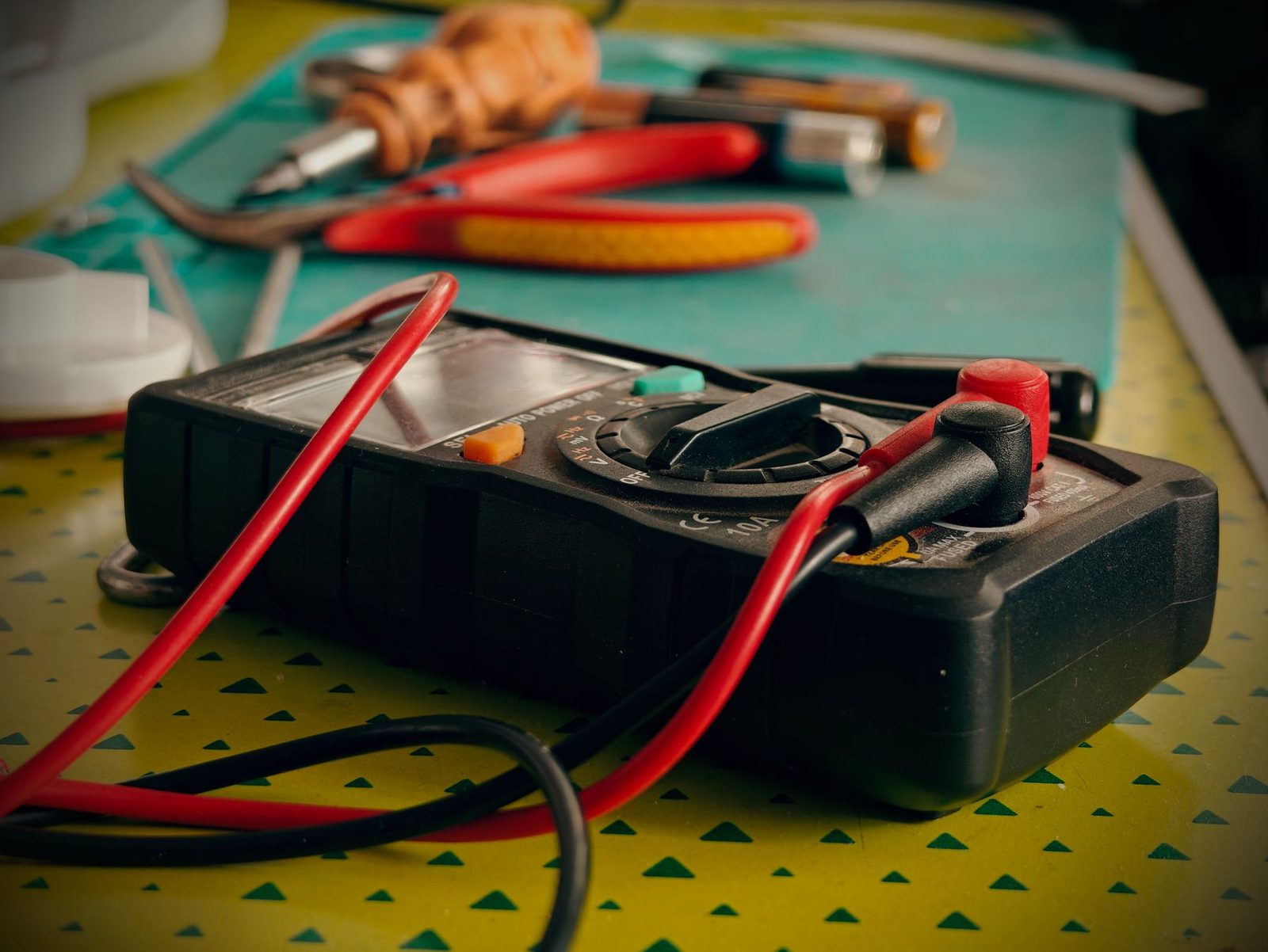 Digital multimeter and hand tools on a technician's bench