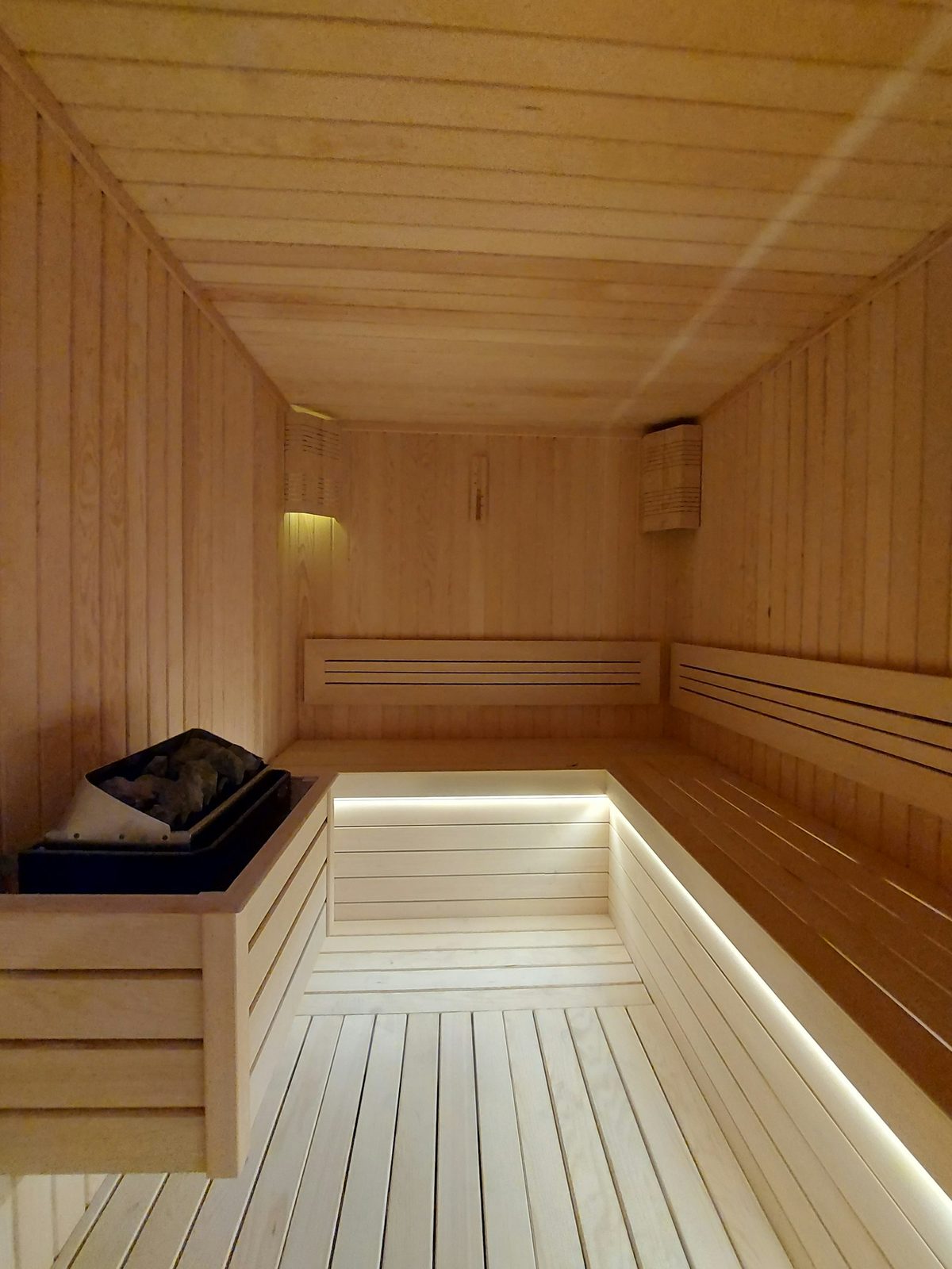 Light wood home sauna with bench lighting